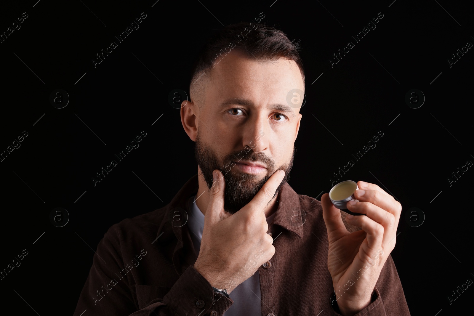 Photo of Handsome bearded man with balm on black background