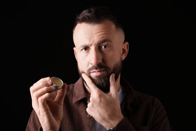 Photo of Handsome bearded man with balm on black background