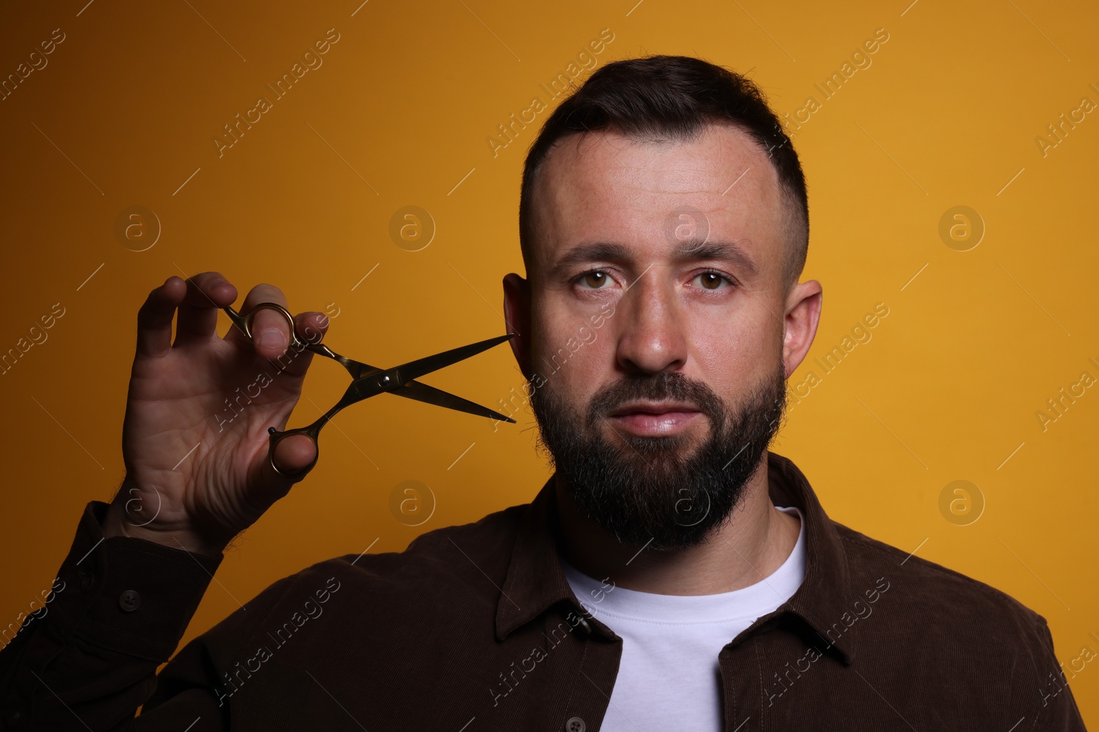 Photo of Bearded man with scissors on orange background