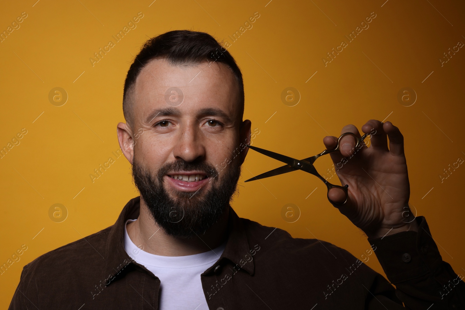 Photo of Bearded man with scissors on orange background