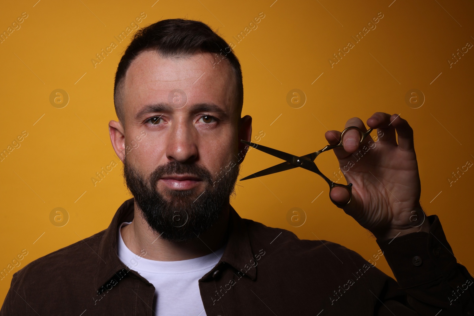 Photo of Bearded man with scissors on orange background