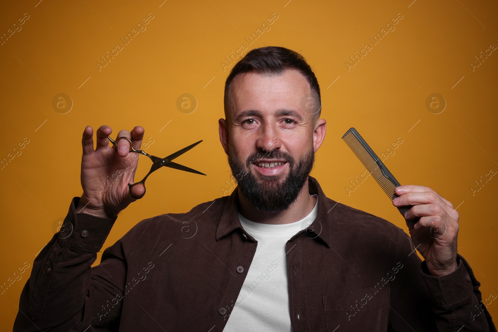 Photo of Bearded man with scissors on orange background