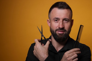 Photo of Bearded man holding comb and scissors on orange background, space for text