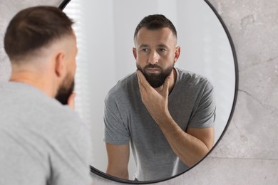 Handsome bearded man near mirror in bathroom