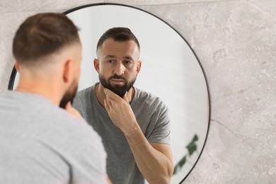 Handsome bearded man near mirror in bathroom