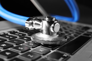 Photo of Technical support concept. Stethoscope on laptop keyboard, closeup