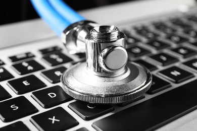 Photo of Technical support concept. Stethoscope on laptop keyboard, closeup