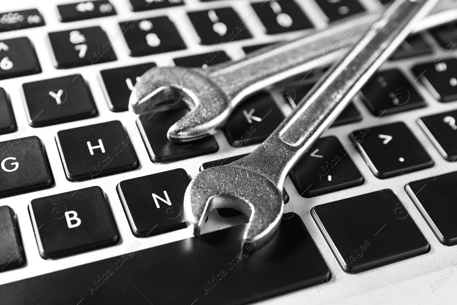 Photo of Technical support concept. Wrenches on laptop keyboard, closeup