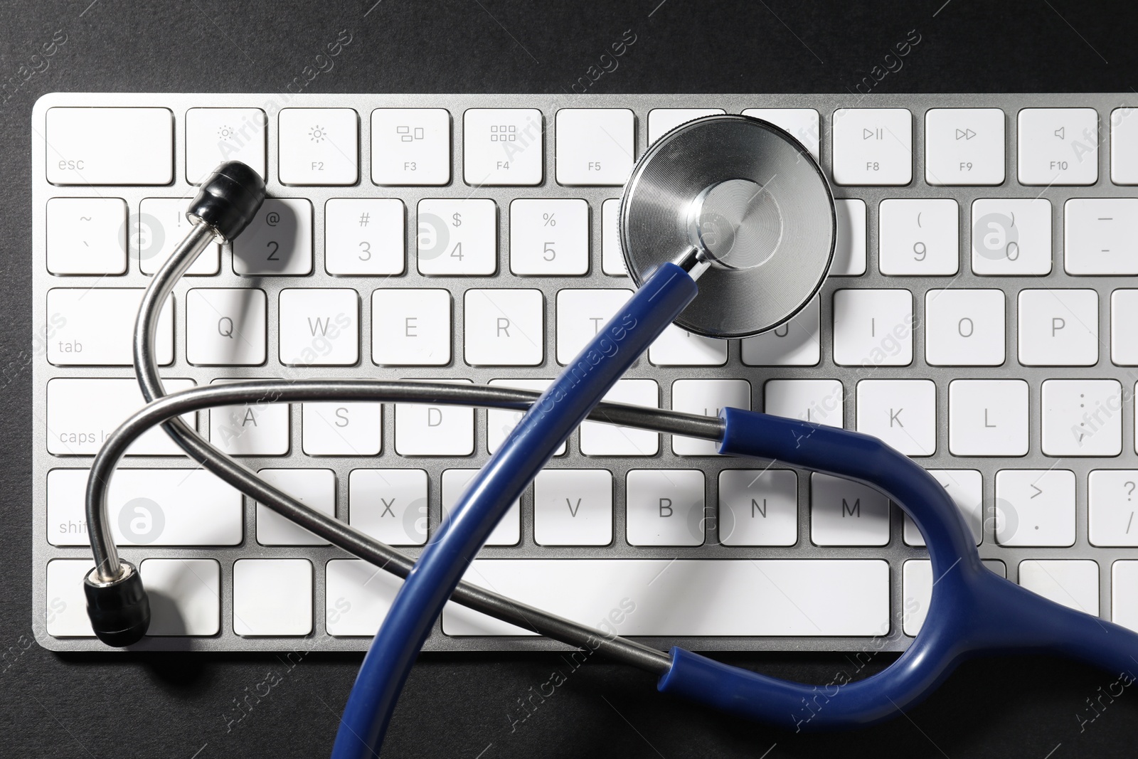 Photo of Technical support concept. Stethoscope and keyboard on black background, top view