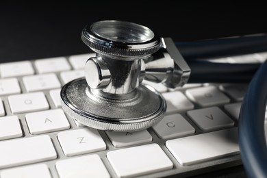 Photo of Technical support concept. Stethoscope and keyboard on black background, closeup