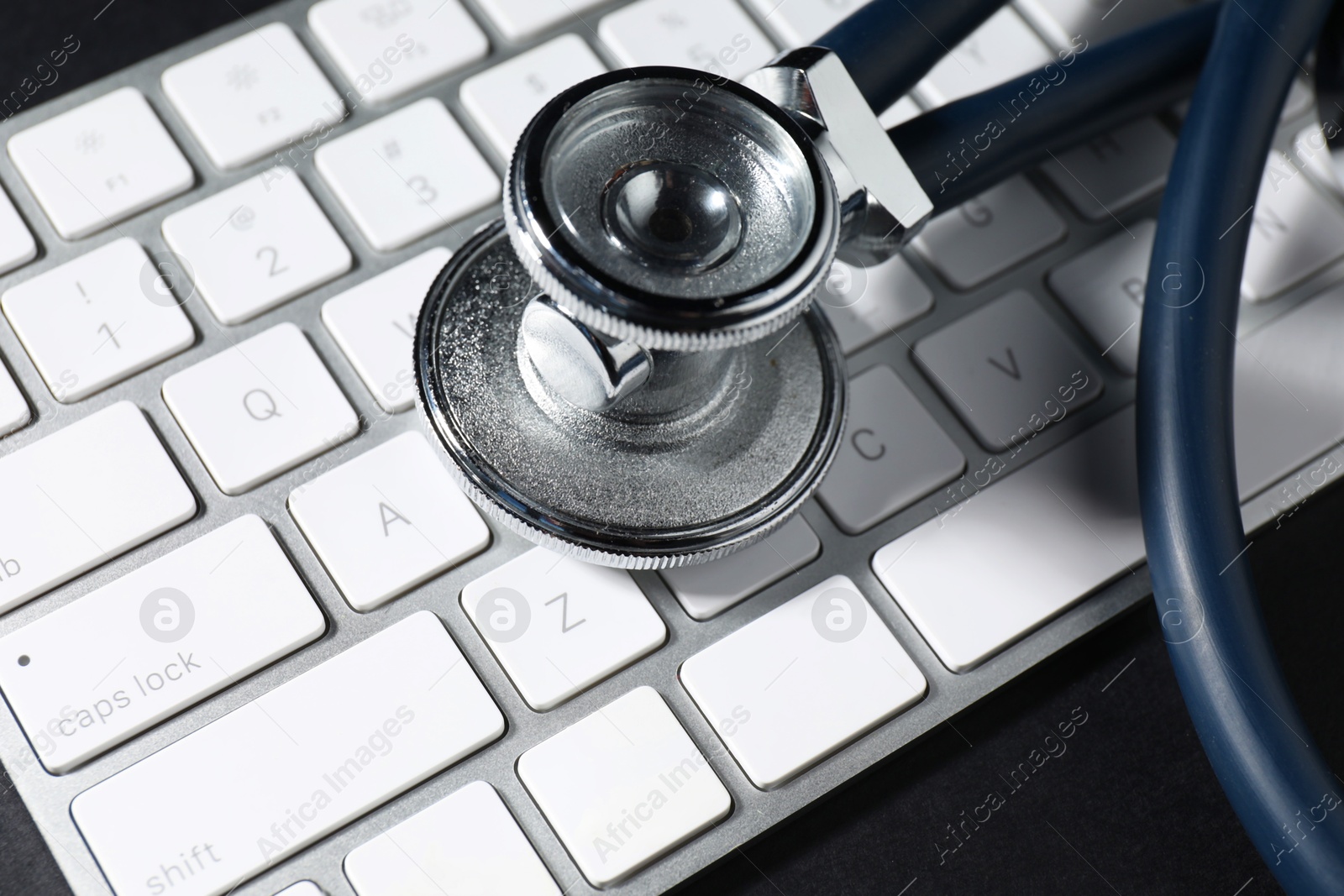 Photo of Technical support concept. Stethoscope and keyboard on black background, closeup