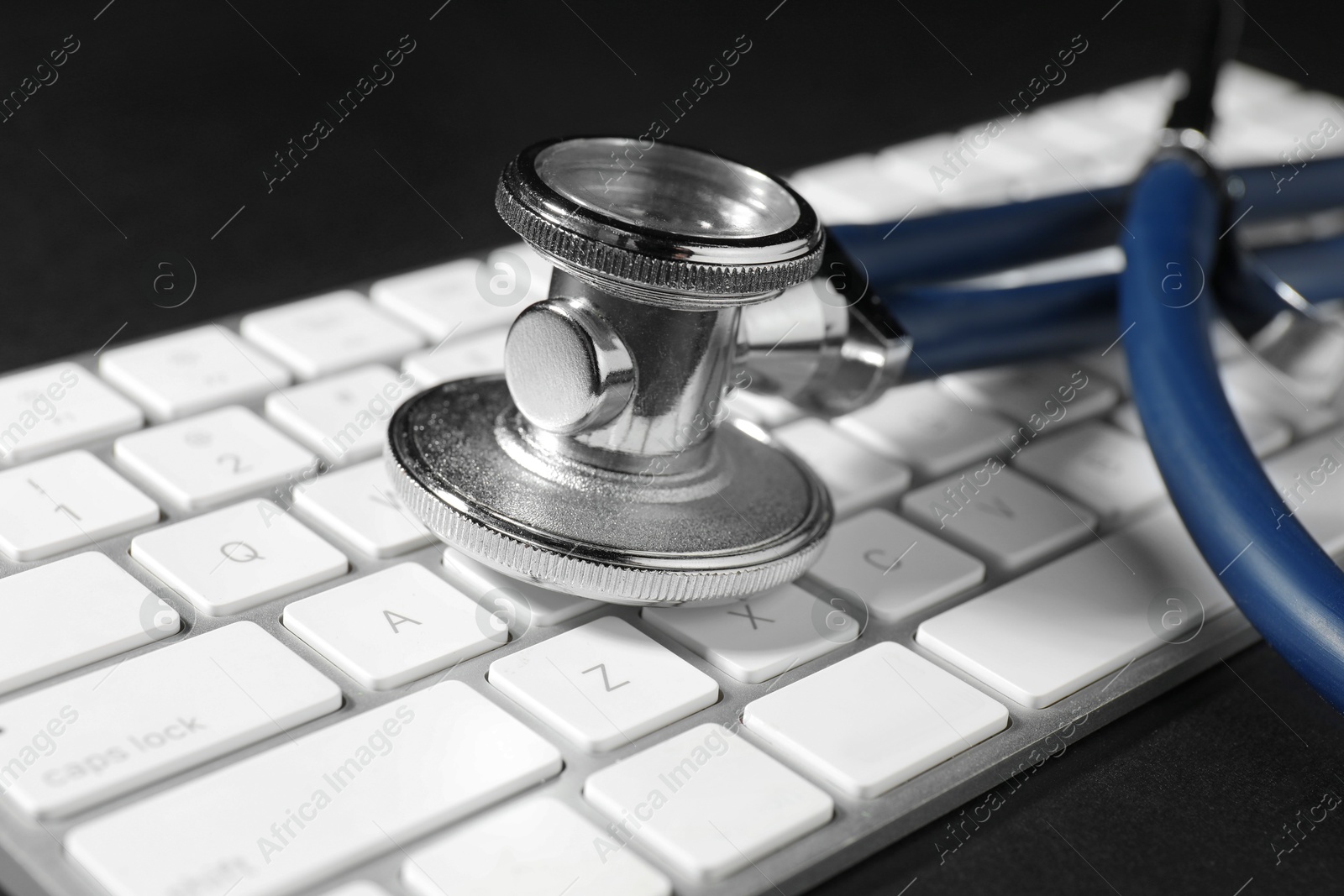 Photo of Technical support concept. Stethoscope and keyboard on black background, closeup