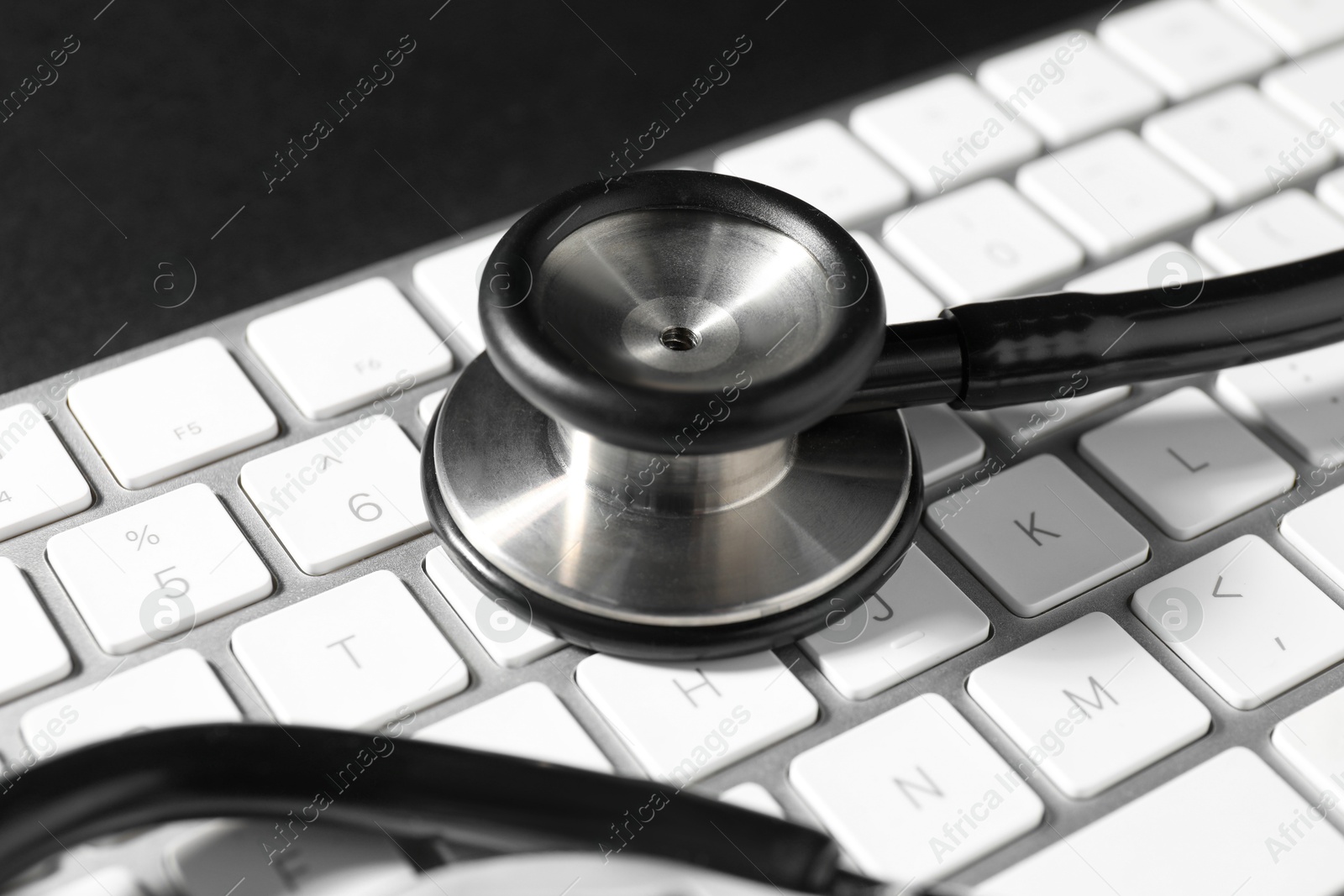 Photo of Technical support concept. Stethoscope and keyboard on black background, closeup