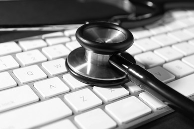 Photo of Technical support concept. Stethoscope and keyboard on black background, closeup