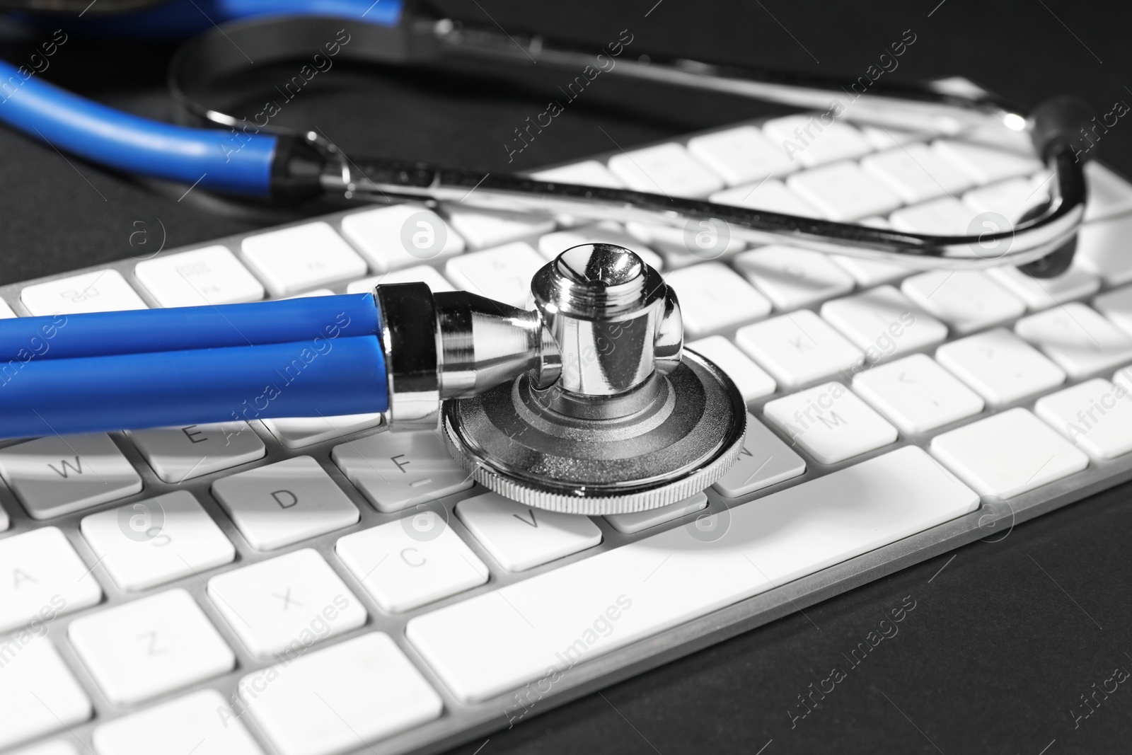 Photo of Technical support concept. Stethoscope and keyboard on black background, closeup