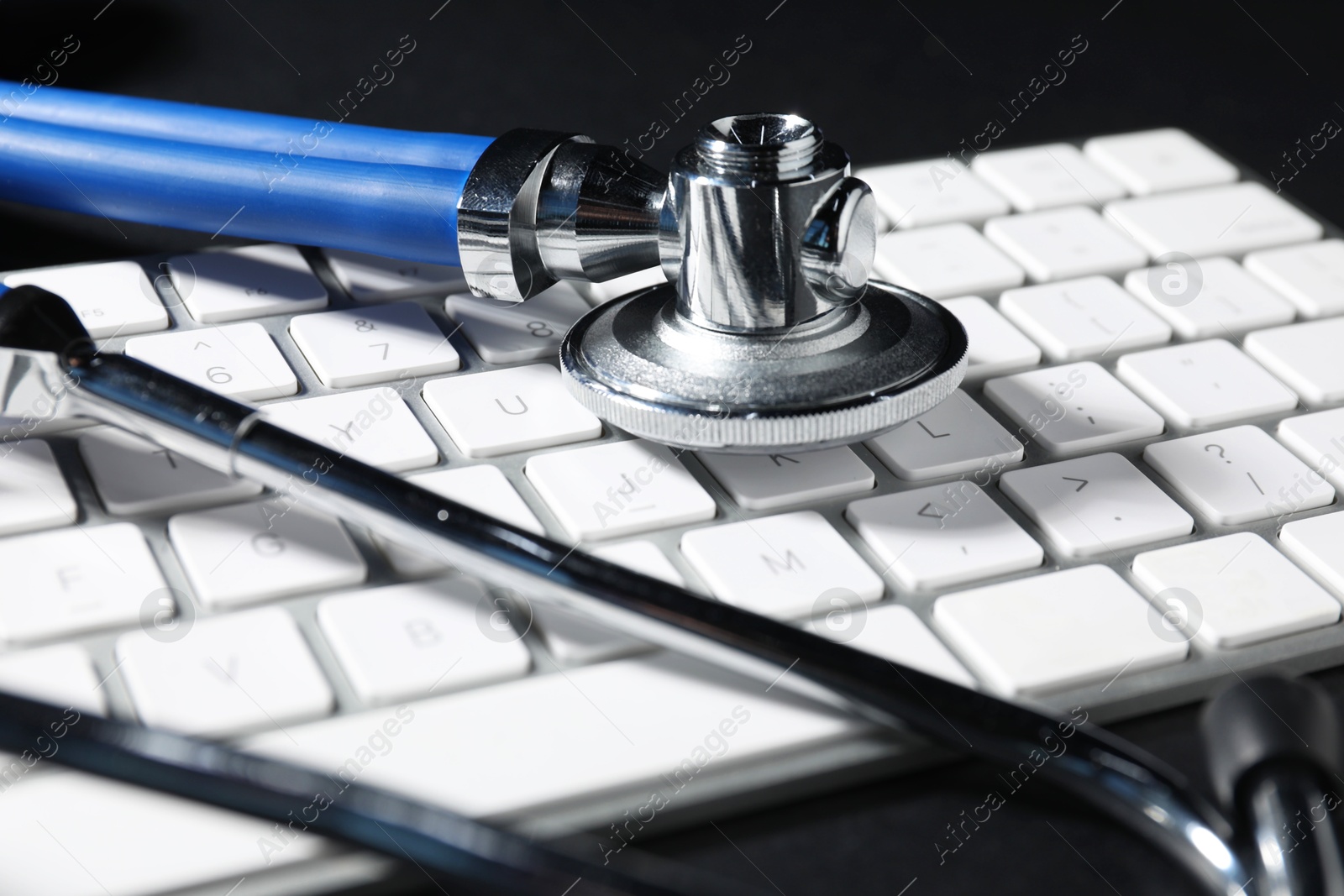 Photo of Technical support concept. Stethoscope and keyboard on black background, closeup