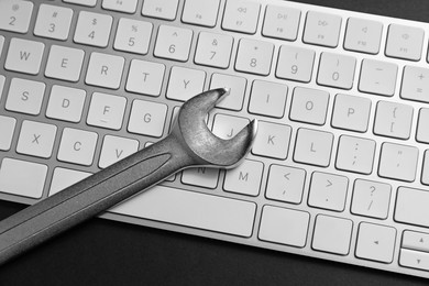 Photo of Technical support concept. Wrench and keyboard on black background, top view