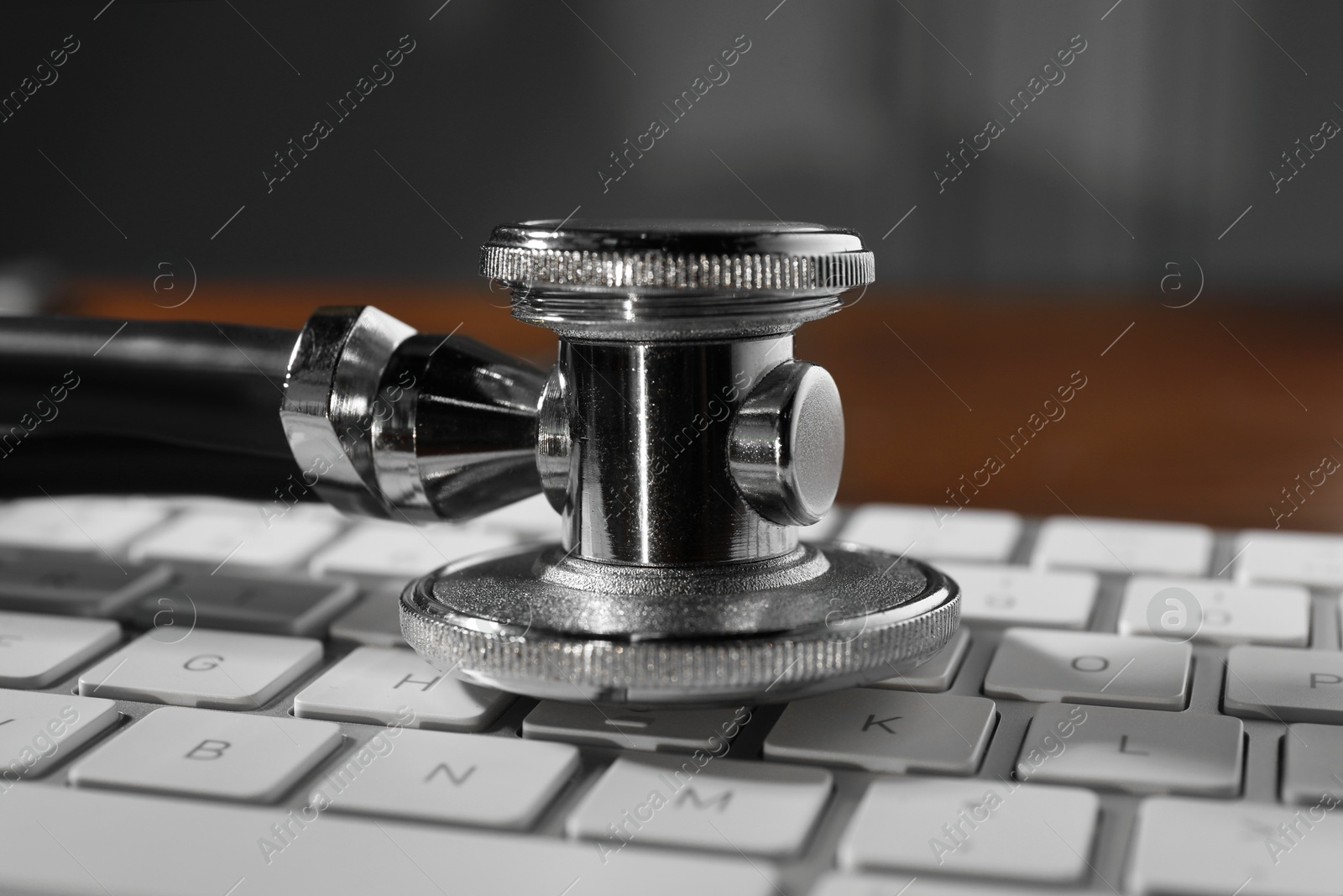 Photo of Technical support concept. Stethoscope and keyboard on wooden table, closeup