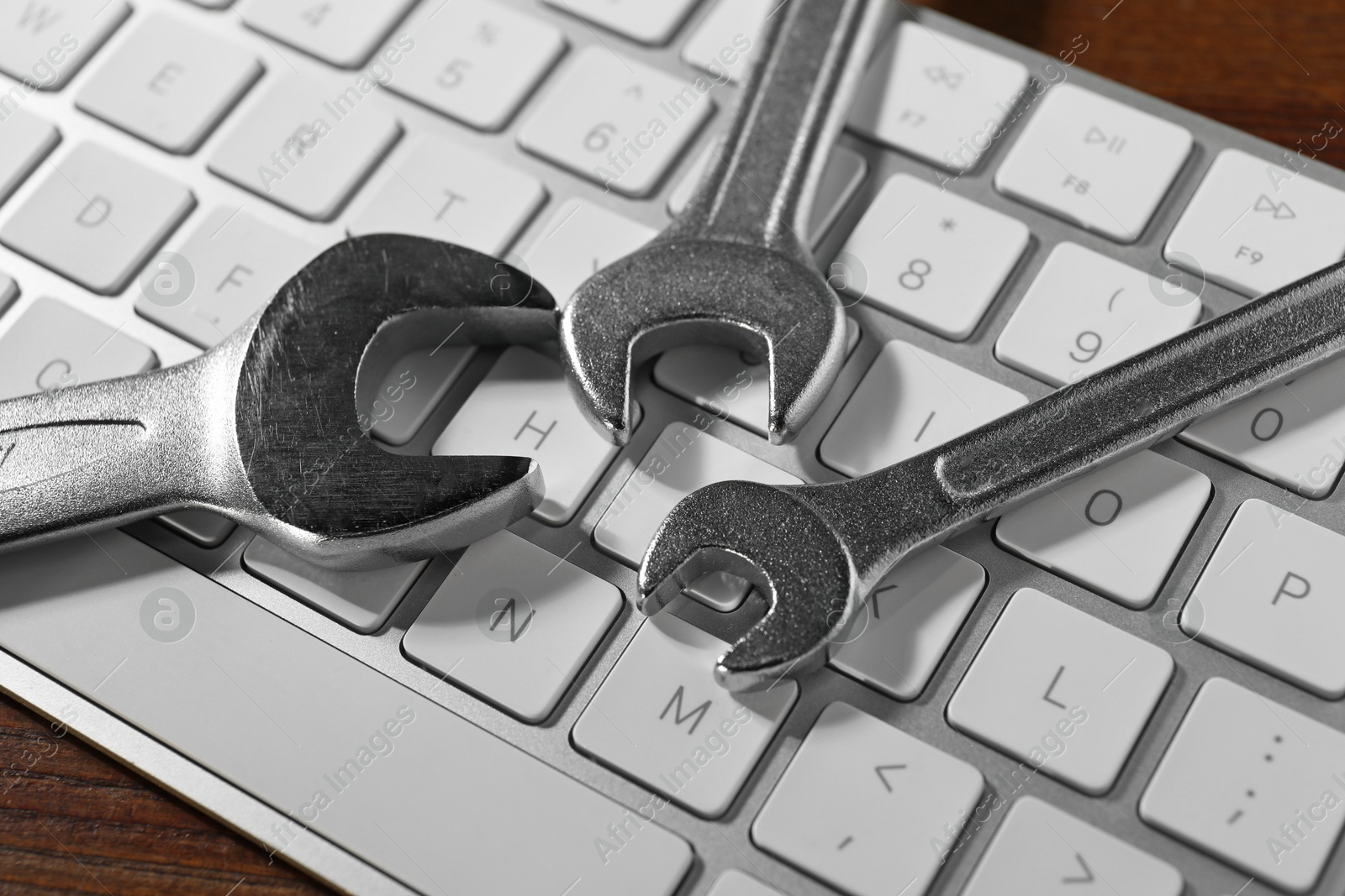 Photo of Technical support concept. Wrenches and keyboard on wooden background, closeup