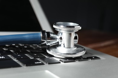 Photo of Technical support concept. Stethoscope on laptop keyboard, closeup