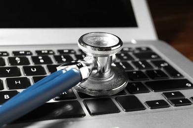 Photo of Technical support concept. Stethoscope on laptop keyboard, closeup