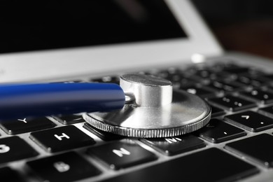 Photo of Technical support concept. Stethoscope on laptop keyboard, closeup