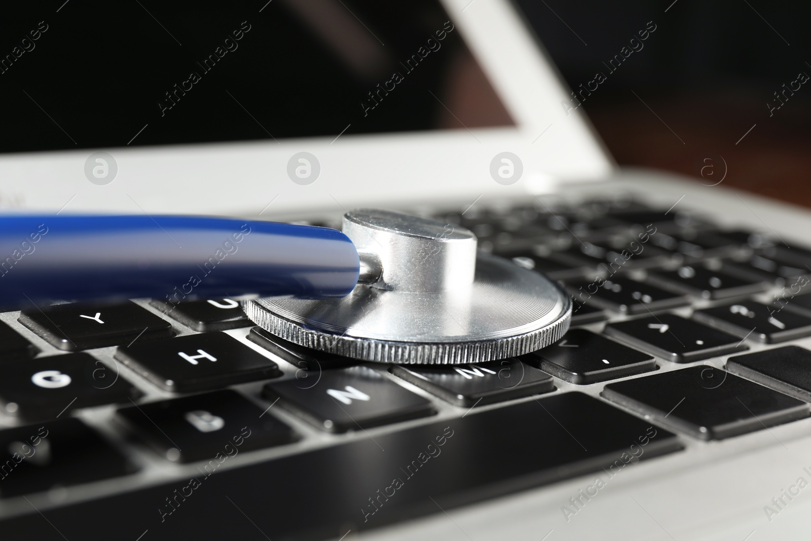 Photo of Technical support concept. Stethoscope on laptop keyboard, closeup