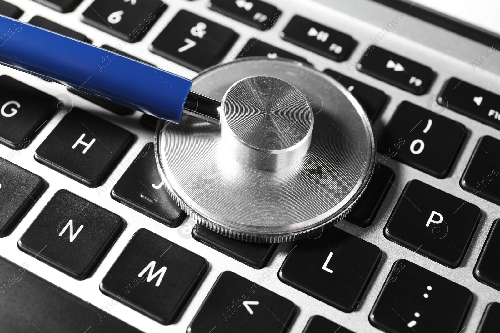 Photo of Technical support concept. Stethoscope on laptop keyboard, closeup