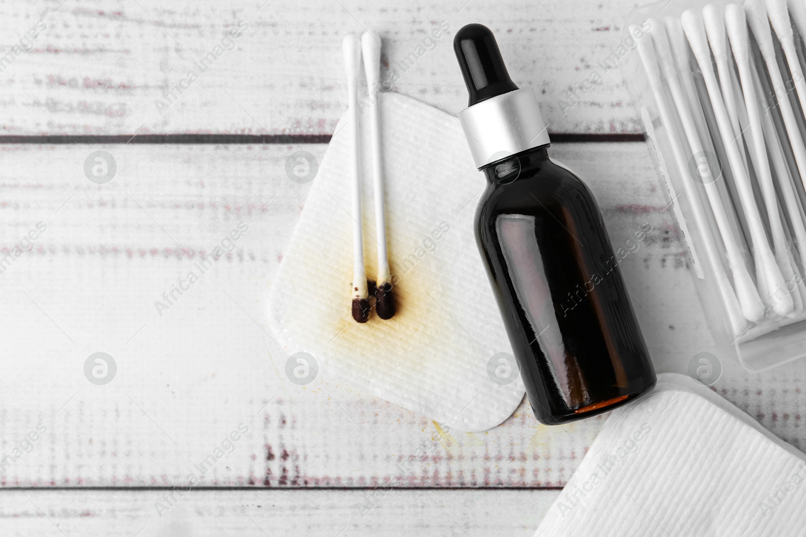 Photo of Bottle of iodine with dropper, cotton pads and swabs on white wooden table, flat lay