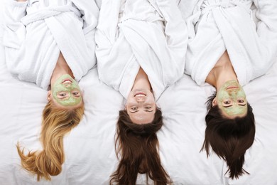 Photo of Spa day. Beautiful woman with face masks on bed, above view