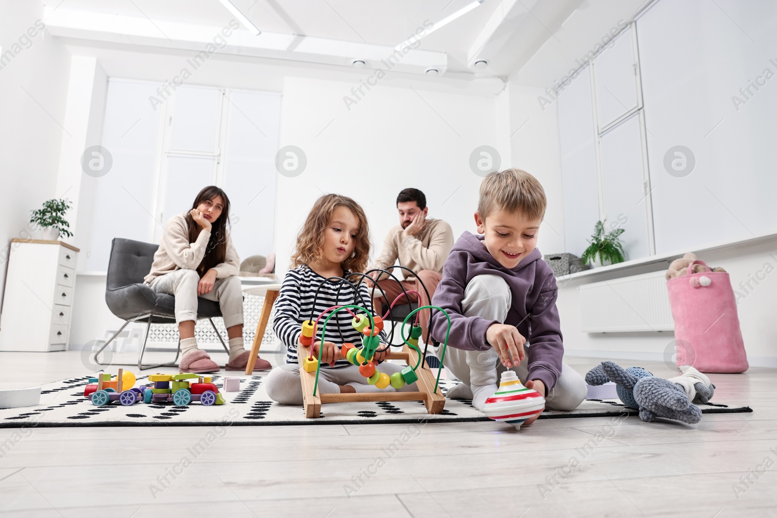 Photo of Hyperactive children playing and their overwhelmed parents at home, low angle view