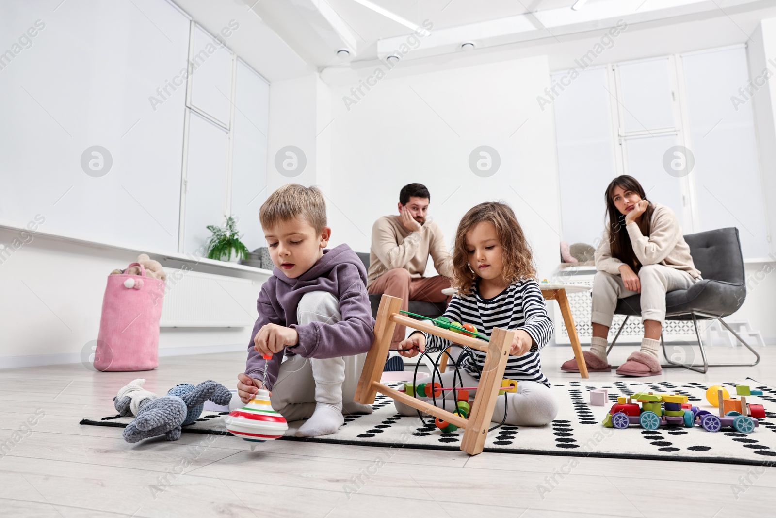 Photo of Hyperactive children playing and their overwhelmed parents at home, low angle view