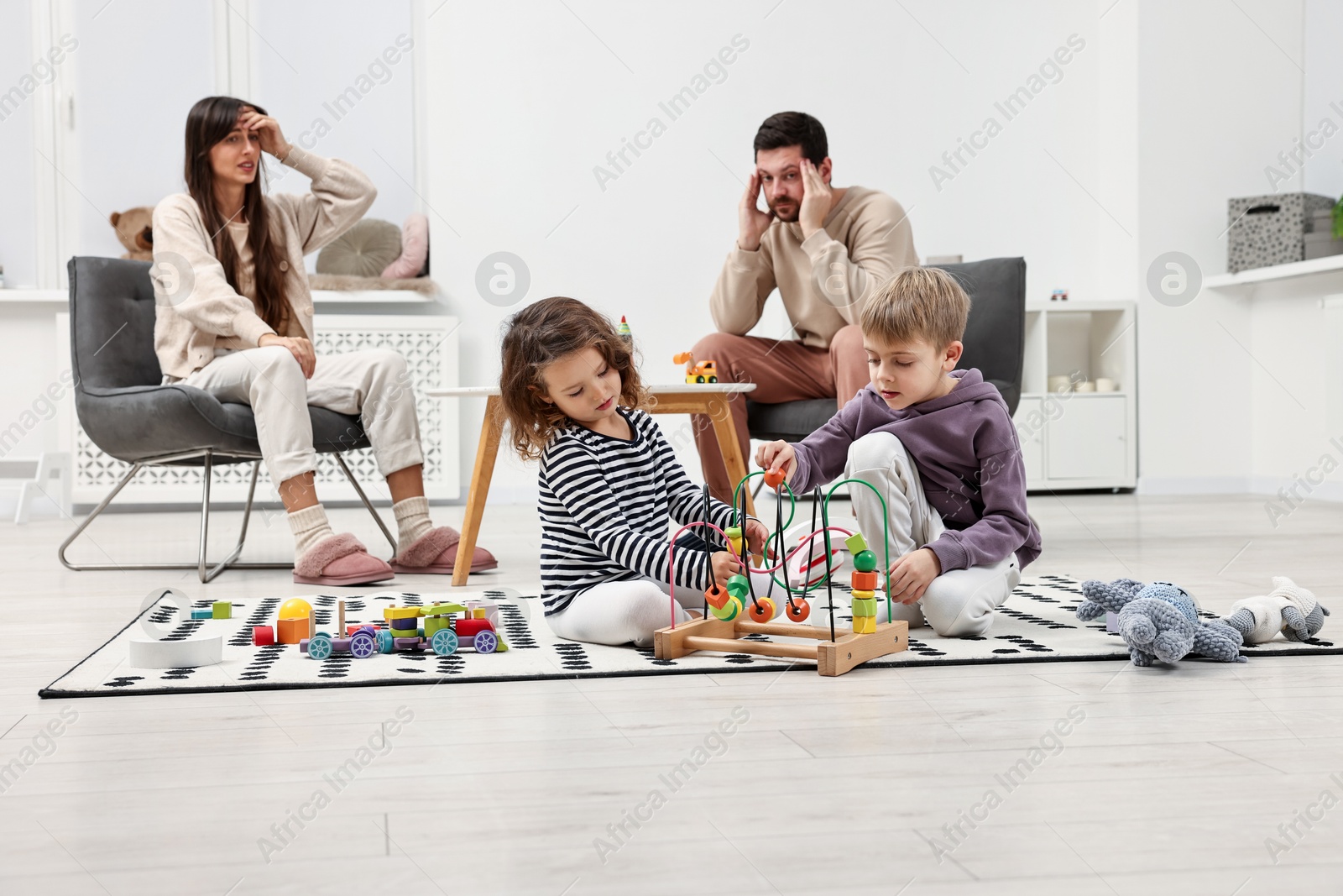 Photo of Overwhelmed parents looking at their hyperactive children at home