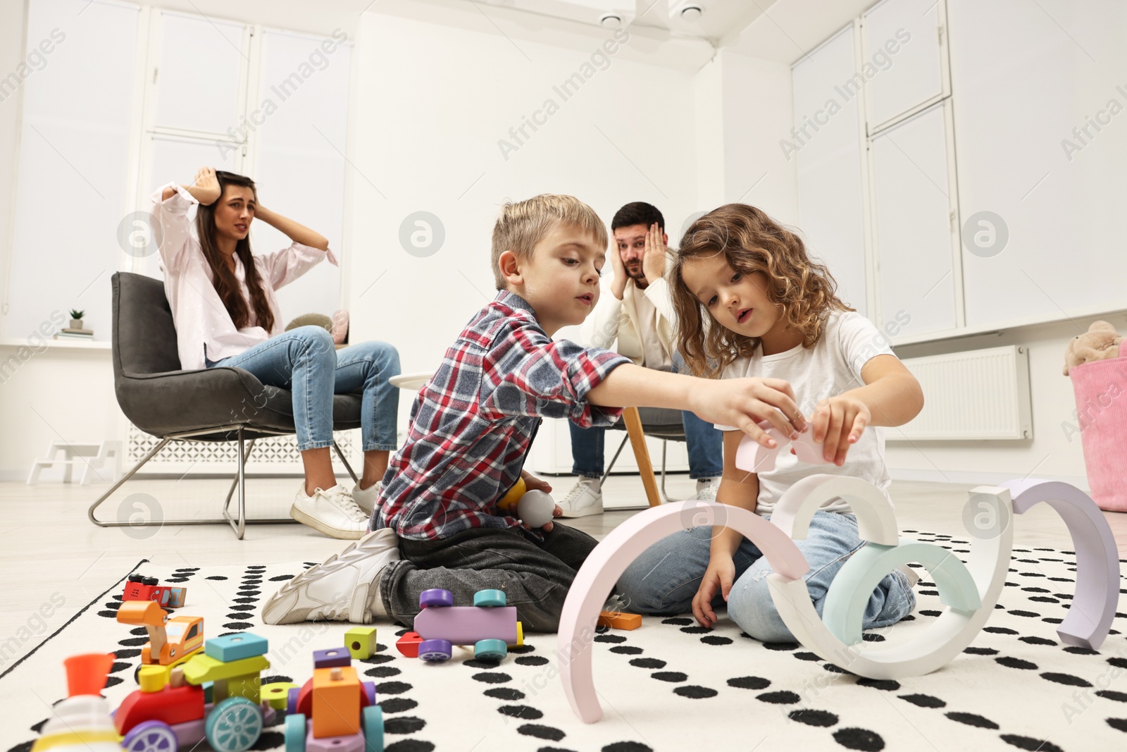 Photo of Hyperactive children playing and their overwhelmed parents at home, low angle view