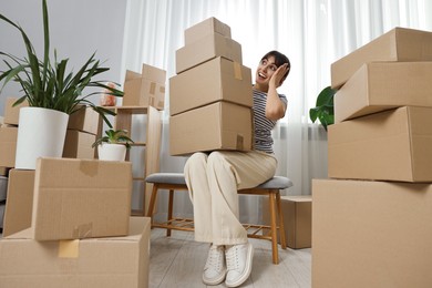 Photo of Moving day. Happy woman with cardboard boxes in her new home