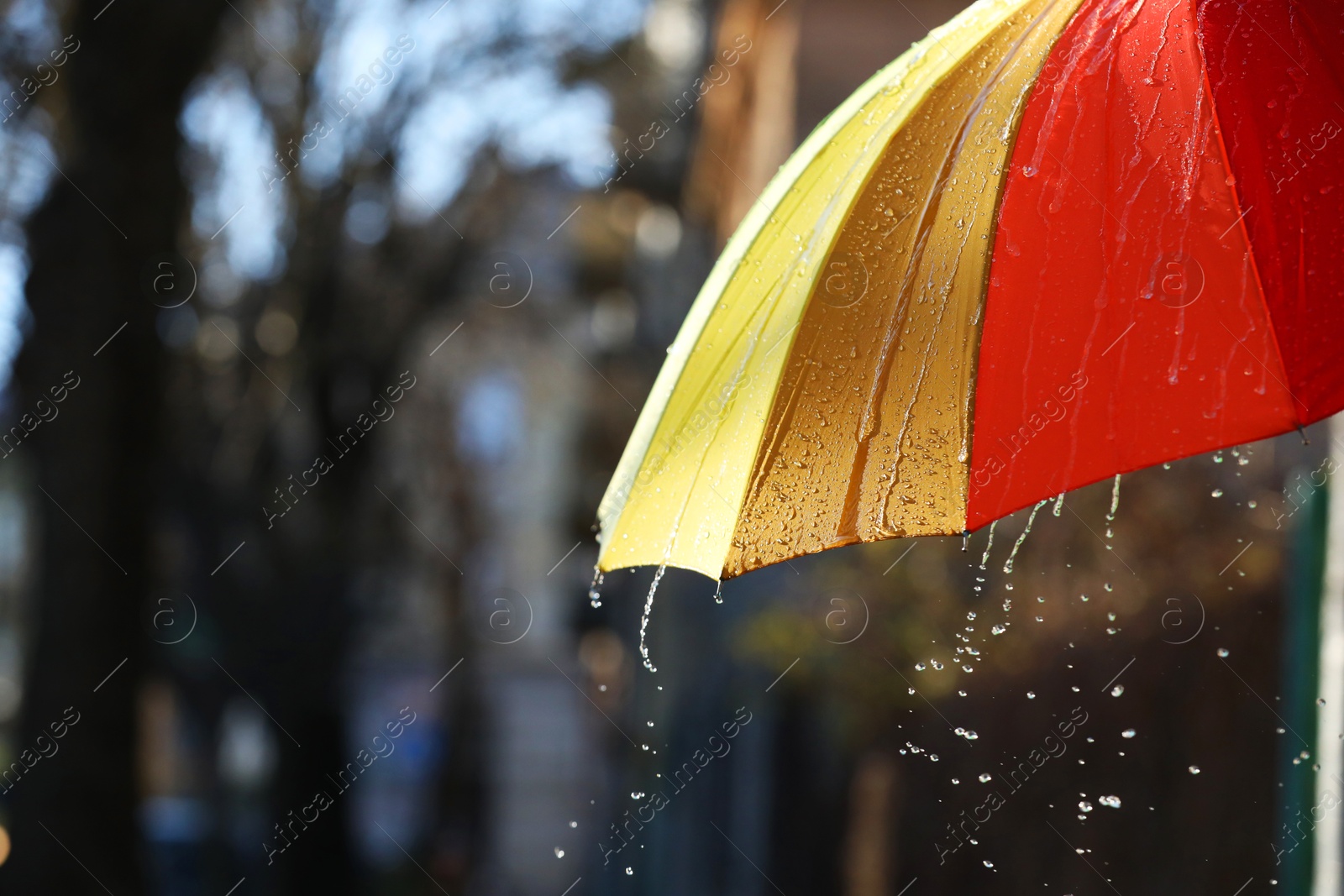 Photo of Open bright umbrella under pouring rain outdoors, closeup. Space for text