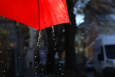 Photo of Open red umbrella under pouring rain outdoors, closeup. Space for text