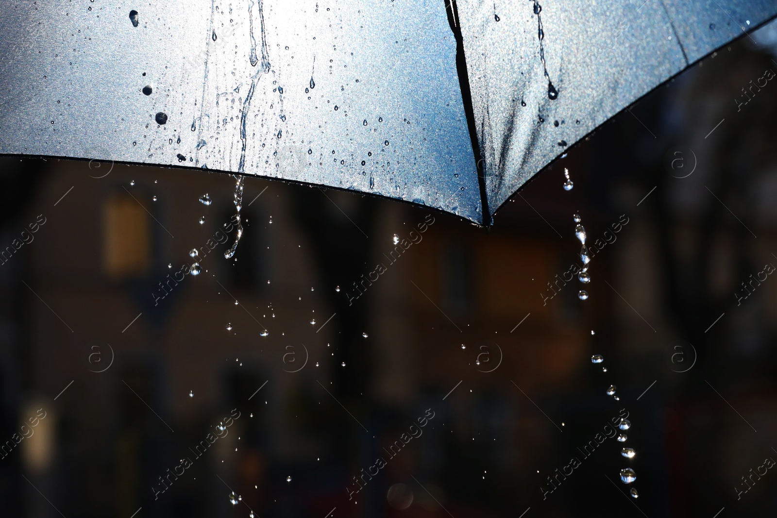 Photo of Open umbrella under pouring rain outdoors, closeup