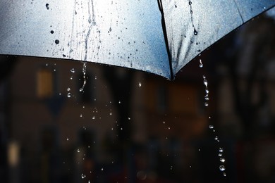 Photo of Open umbrella under pouring rain outdoors, closeup