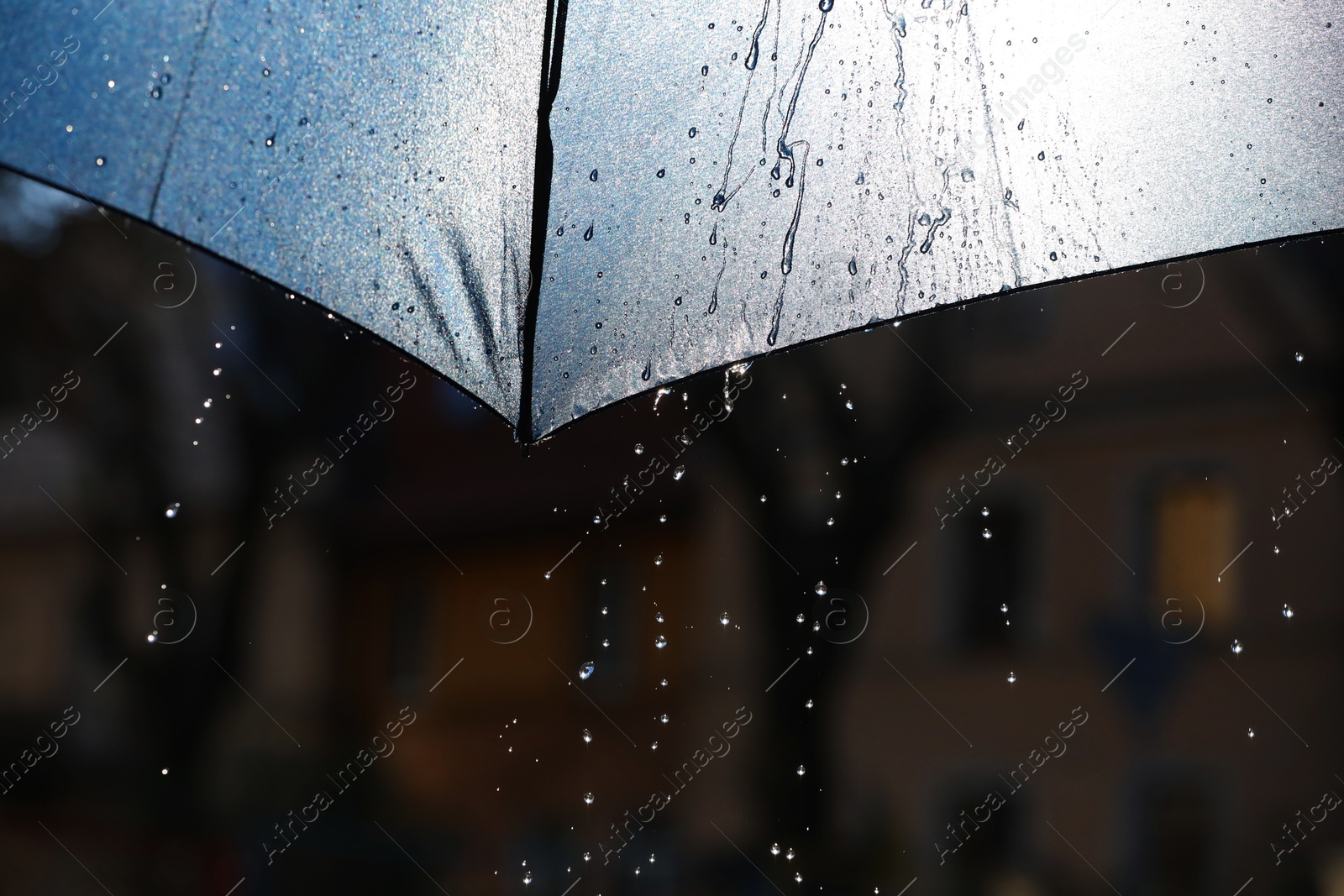 Photo of Open umbrella under pouring rain outdoors, closeup