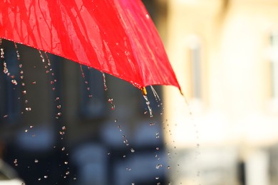 Photo of Open red umbrella under pouring rain outdoors, closeup. Space for text