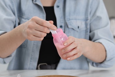 Photo of Mother making baby formula in feeding bottle at table indoors, closeup