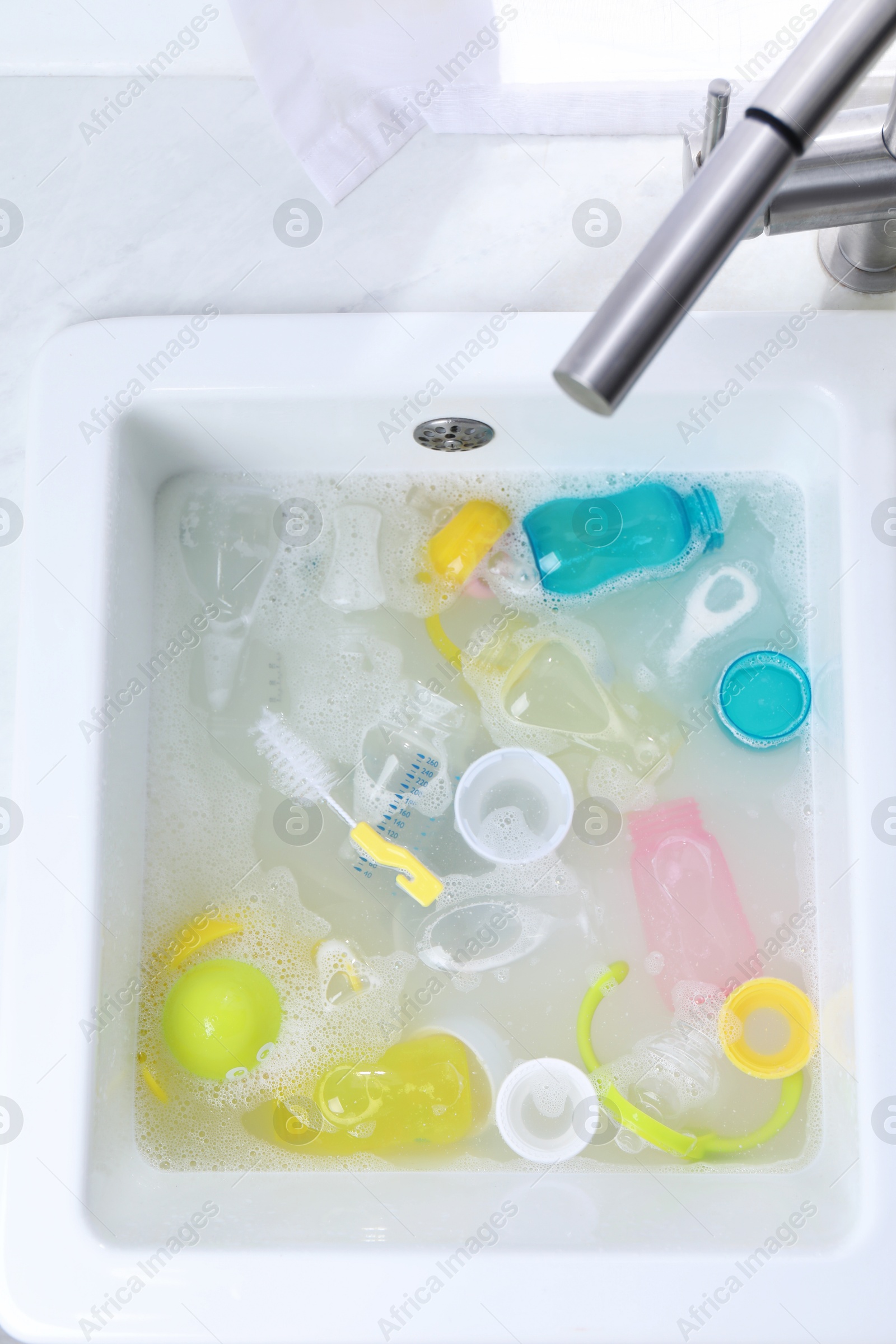 Photo of Washing feeding bottles in sink, top view