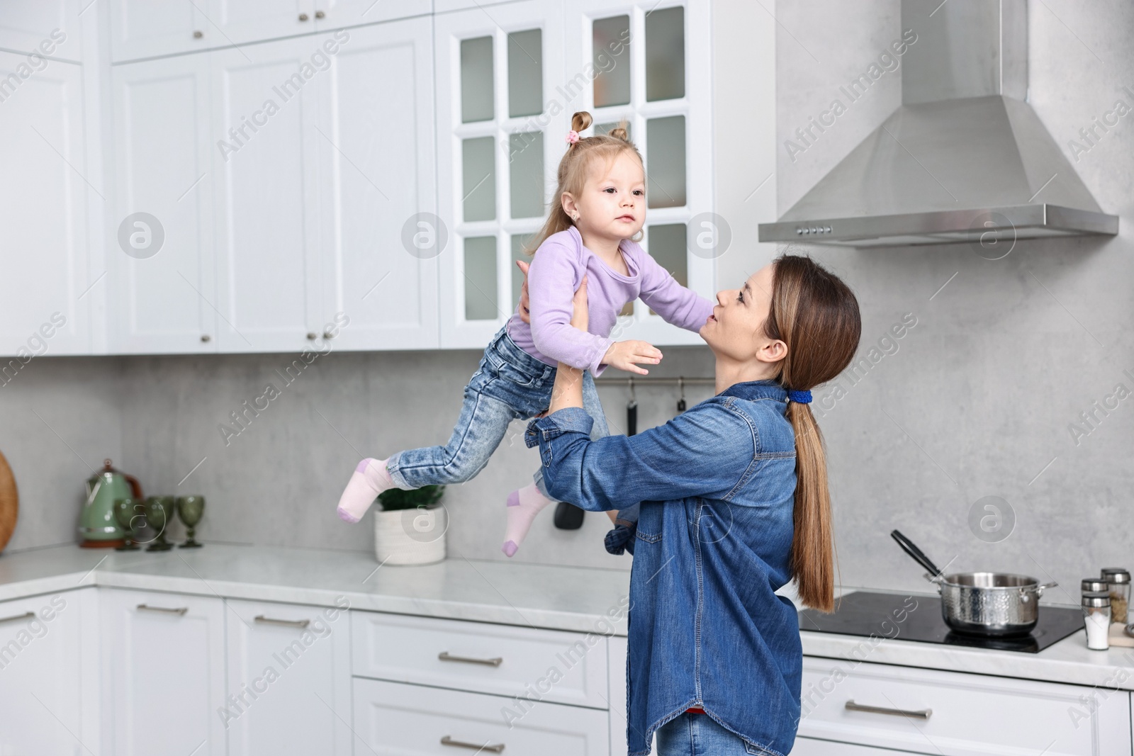 Photo of Housewife playing with her little daughter in kitchen