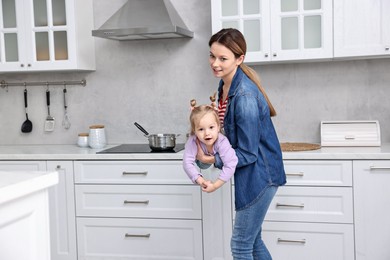 Photo of Housewife playing with her little daughter in kitchen