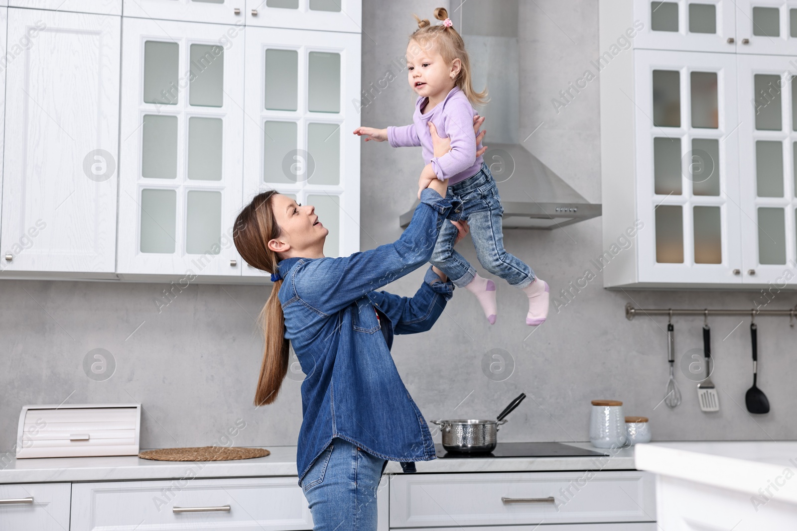 Photo of Happy housewife playing with her little daughter in kitchen