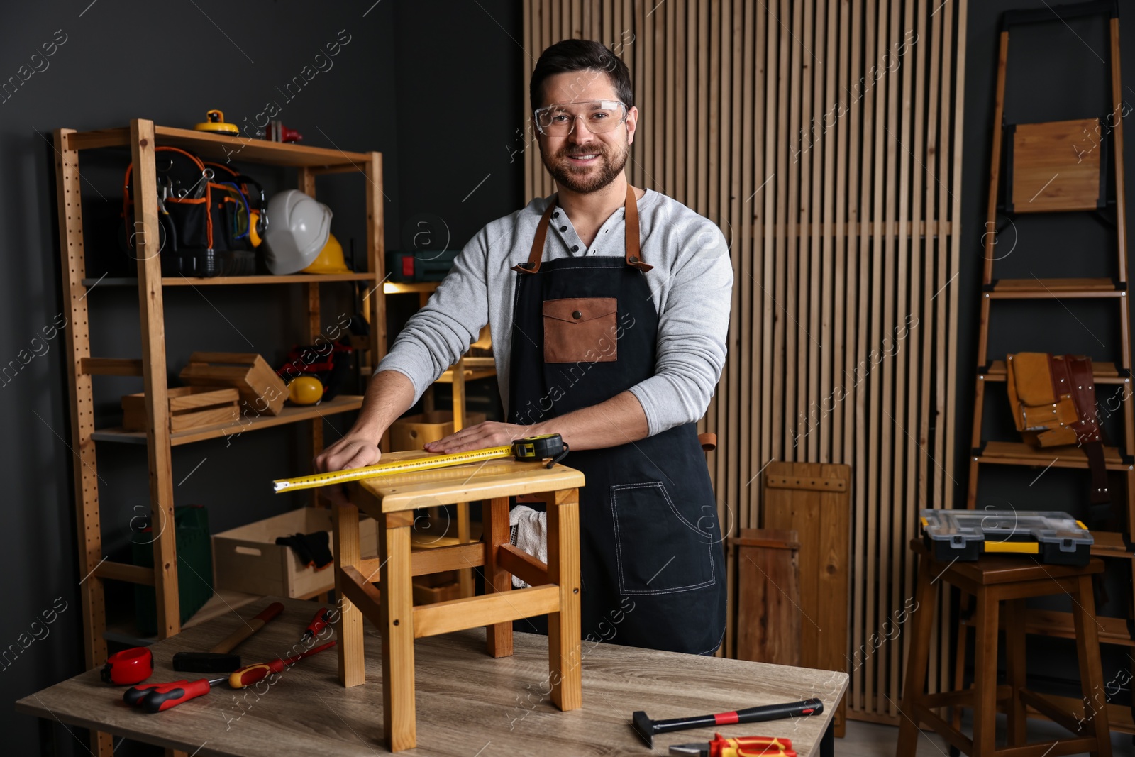 Photo of Professional repairman with wooden stool and tools in workshop