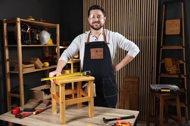 Photo of Professional repairman with wooden stool and tools in workshop