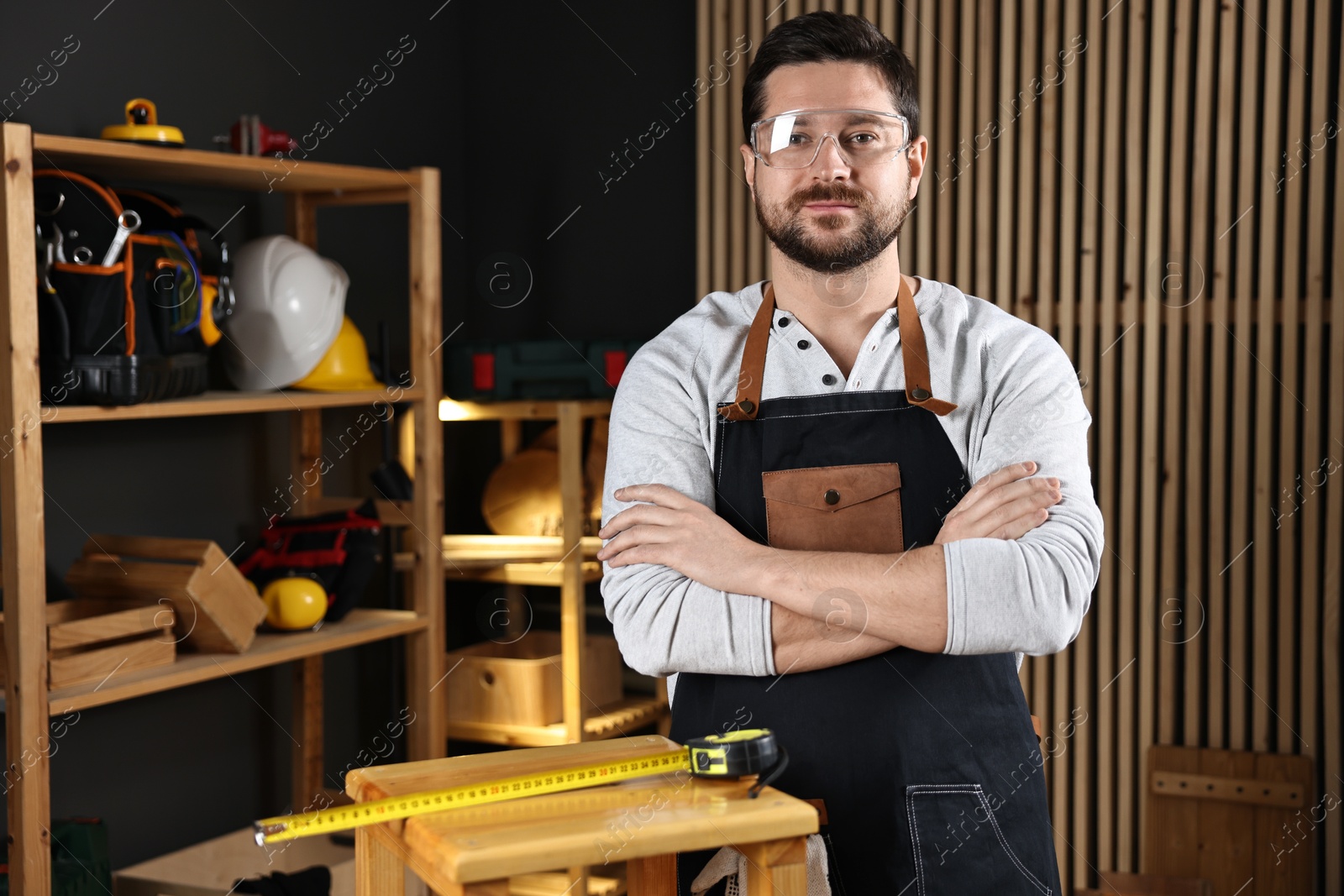 Photo of Professional repairman with wooden stool and tool in workshop