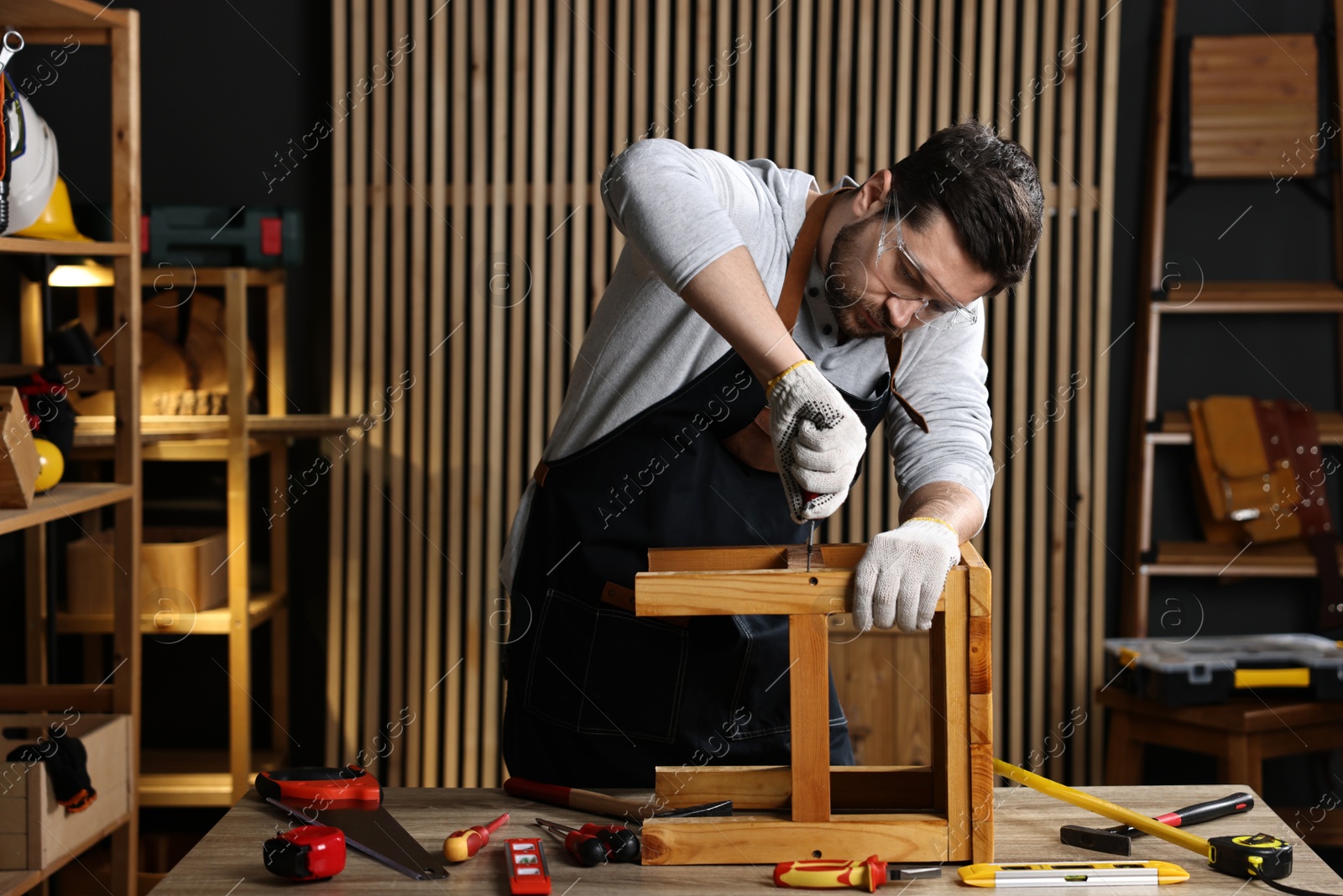 Photo of Carpenter repairing stool at table in workshop